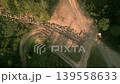 Aerial top down view of a large flock of sheep walking along a dirt mountain road near a pine forest during sunset traditional animal husbandry in highlands 139558633