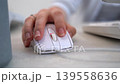 Close up of female hand using a white computer mouse on a light office desk professional worker navigating digital interface or editing content in workspace 139558636