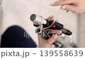 Vertical frame close up of professional cosmetologist hands in gloves changing and installing alexandrite laser handpiece for hair removal procedure in aesthetic clinic 139558639