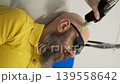 Vertical frame close up of bald bearded man with safety glasses receiving alexandrite laser hair removal on head in professional aesthetic medical clinic 139558642