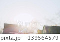 Hand lifting toy aircraft in bright outdoor light. Rural scenery and strong sun flare add travel mood. 139564579