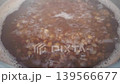 Boiling grains in a pot with bubbling water and floating foam, showcasing the cooking process in a kitchen setting with visible steam rising 139566677