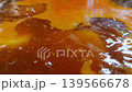 Close-up view of simmering liquid with bubbles and vibrant orange hues, showcasing the gradual movement and texture of the mixture in a cooking pot 139566678