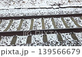 Snow-covered railway tracks with gravel and wooden ties visible, showing the continuous perspective of the train journey through a winter landscape 139566679