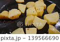 Chopped yellow potatoes cooking in a frying pan with oil and spices, showing gradual browning and texture changes in a kitchen setting 139566690