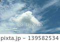 A beautiful soft white cloud floats against a bright blue sky, surrounded by wispy clouds, creating a serene and tranquil atmosphere perfect for nature lovers. 139582534