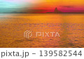A stunning sunset scene featuring vibrant colors reflecting on calm waters. The silhouette of distant landscape adds depth to this tranquil and serene vista, perfect for evoking feelings of peace and  139582544