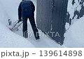 man clearing snow in countryside using electric snow blower. Snowing weather conditions 139614898