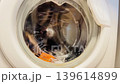 laundry tumbling and swirling behind the circular glass door of a modern washing machine with a steady hum sound 139614899