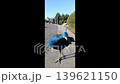 a colorful Indian peacock walking along a stone pathway outdoors in a sunny park during daylight. Natural exotic bird behavior with greenery in the background. 139621150