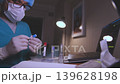 Medical doctor working late analyzing blood samples 139628198