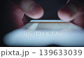 A man is looking at images on his smartphone at night, close-up of his hands, front view 139633039