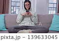 Serious Young Woman Sitting Alone with Phone Indoors 139633045