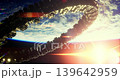 A massive circular structure orbits Earth, illuminated by sunlight breaking through the atmosphere. The view captures the beauty of space as day begins. 139642959