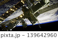 The International Space Station orbits Earth, showcasing its complex structure and illuminated panels. The curve of the planet is visible in the background, highlighting its atmosphere. 139642960