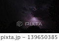 Lightning strikes on a dark night sky over a city landscape, captured in slow motion. 139650385