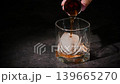 A bartender adds a shot of whiskey to a whiskey glass with ice. The glass is captured close-up. Realistic footage of the Manhattan cocktail being prepared demonstrates the step-by-step process 139665270