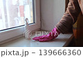 Person in pink gloves cleaning mold on window sill and walls using antifungal spray. Removing toxic black mold and mildew from window frame and plaster. Home maintenance and hygiene. Person in pink gloves cleaning mold on window sill and walls using antifungal spray. Removing toxic black mold and mildew from window frame and plaster. Home maintenance and hygiene. 139666360