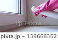 Person in pink gloves cleaning mold on window sill and walls using antifungal spray. Removing toxic black mold and mildew from window frame and plaster. Home maintenance and hygiene. Person in pink gloves cleaning mold on window sill and walls using antifungal spray. Removing toxic black mold and mildew from window frame and plaster. Home maintenance and hygiene. 139666362