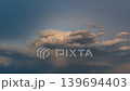 Glowing storm clouds rolling through a richly colored sunset sky scene 139694403