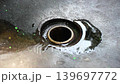 Detail of a black stone sink drain hole flooded with water and traces of green paint around it 139697772