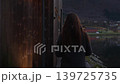Woman Walking Beside Wooden Fjordside Saunas in Skjolden Norway 139725735