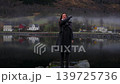 Woman Tossing Coin into Calm Fjord in Skjolden Norway 139725736
