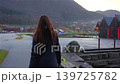 Woman Walking Toward Wooden Cabins on Fjord Waterfront in Skjolden Norway 139725782