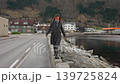 Smiling Woman Balancing on Stone Wall by Fjord Waterfront 139725824
