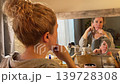 Woman Practicing Facial Yoga in Front of Mirror Woman Practicing Facial Yoga in Front of Mirror 139728308
