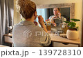 Woman Practicing Facial Yoga in Front of Mirror Woman Practicing Facial Yoga in Front of Mirror 139728310