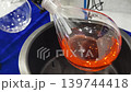 Chemical reaction demonstration showing colorful liquid in glass container near equipment in lab setting 139744418