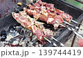 Grilling delicious skewered meat on an outdoor barbecue at summer gathering 139744419