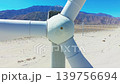 Drone shot of rotating wind turbine blades in Palm Springs desert with mountain landscape and blue sky backdrop 139756694