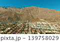 Drone aerial panorama of Palm Springs mountains rising above desert city landscape under clear blue California sky 139758029