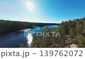 Cinematic FPV drone flight slowly approaching Kolmoislampi lake surrounded by pine forest and rocky shoreline in Nuuksio, Finland. 139762072