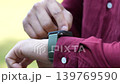 The close up of a man wearing a smartwatch on his left wrist and using this device outside. Electric gadget and a user shot on blurry background. 139769590