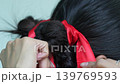 Closeup of braided hairstyle tied with bright red ribbon. Traditional hair decoration with smooth black hair and detailed texture. 139769593