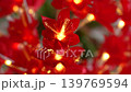 Artificial red decorative flowers with glowing orange yellow fiber lights inside the petals. Festive floral ornament with warm illumination and soft background blur. 139769594