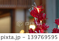 Artificial red decorative flowers with glowing orange yellow fiber lights inside the petals. Festive floral ornament with warm illumination and soft background blur. 139769595