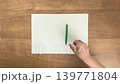 A child's hand picking up a green pen from an A4 sheet of paper, in 4K slow motion, silent. 139771804