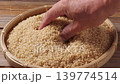特寫鏡頭：雙手輕輕觸摸放在竹籃裡的糙米，檢查其品質。 139774514