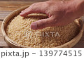 一隻手從竹籃裡舀起糙米，讓人聯想到豐收和健康飲食。 139774515