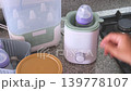 Parent using a bottle warmer for baby milk in the kitchen 139778107