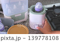 Person using electric baby bottle warmer in kitchen 139778108