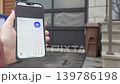 Hand holding smartphone displaying garage door control interface, showing progression of door opening in residential driveway setting 139786198