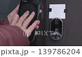 Person using smartphone to control smart lock on front door, showing unlocking, locking, and locked status in a residential setting 139786204