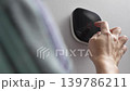 Hand adjusts modern digital thermostat on a wall, displaying temperature settings in a cozy indoor environment with soft lighting 139786211
