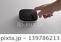 Hand adjusts digital thermostat display showing temperature change from 20F to 21F on a clean, white wall in a modern indoor setting 139786213