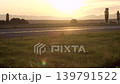 Asphalt road, grass fields on both sides, afternoon sunset sun reflects on ground 139791522